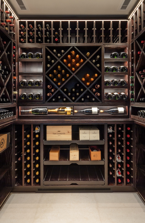 a partially stocked custom wine room featuring dark wood decor
