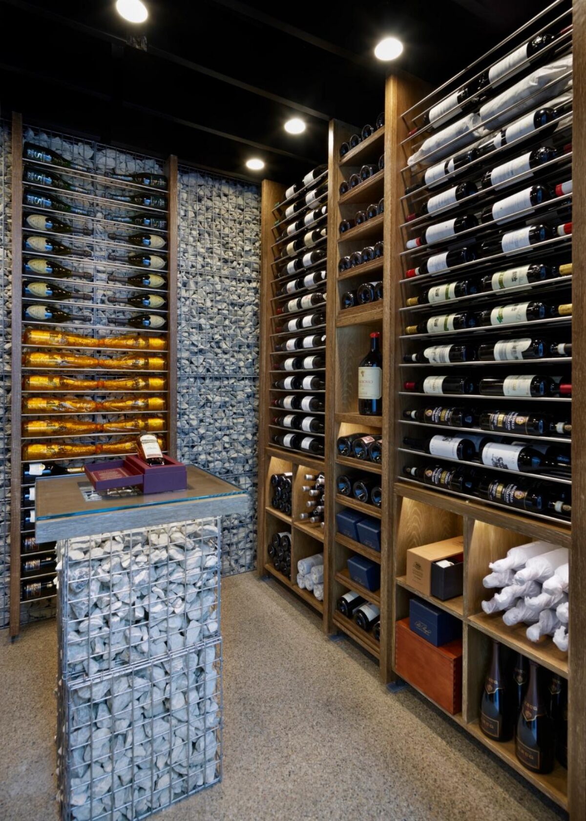 a wine room with wine displays set against loose stone held in place by wire mesh
